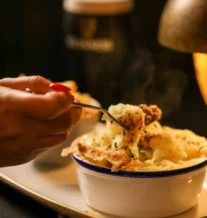 Close-up of a comforting shepherd's pie with a pint of stout.