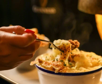 Close-up of a comforting shepherd's pie with a pint of stout.