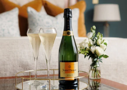 Champagne bottle and glasses on a tray in a cosy hotel room.