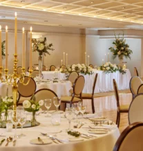 Elegant banquet hall with beautifully set tables, adorned with floral centrepieces and candles.