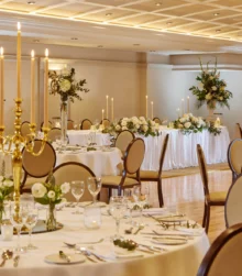 Elegant banquet hall with beautifully set tables, adorned with floral centrepieces and candles.