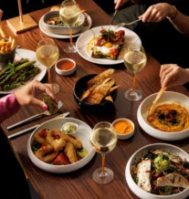 A family enjoying a meal with wine, diverse dishes, and a warm, inviting atmosphere.