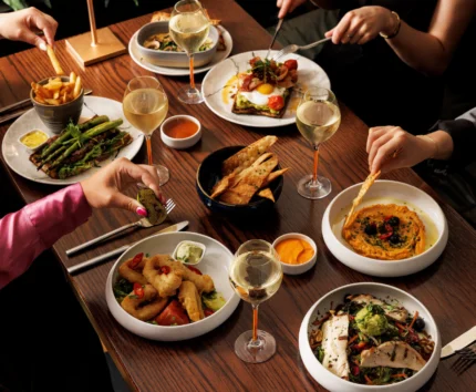 A family enjoying a meal with wine, diverse dishes, and a warm, inviting atmosphere.