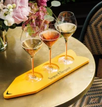 Three glasses of champagne on a golden table with elegant flowers.