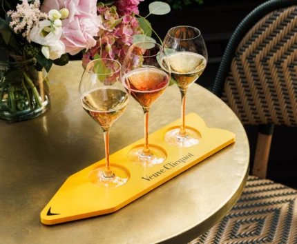 Three glasses of champagne on a golden table with elegant flowers.