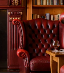 Cosy hotel lounge with red leather chairs and a fireplace.