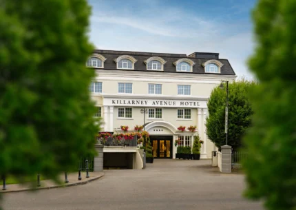 Elegant hotel entrance with guests arriving amidst lush greenery.