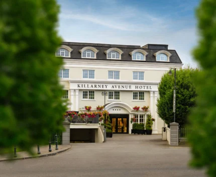 Elegant hotel entrance with guests arriving amidst lush greenery.