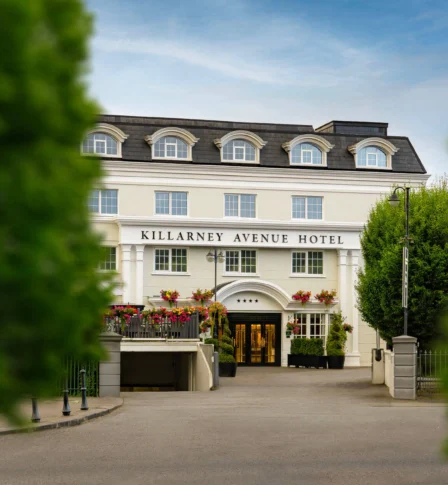 Elegant hotel entrance with guests arriving amidst lush greenery.
