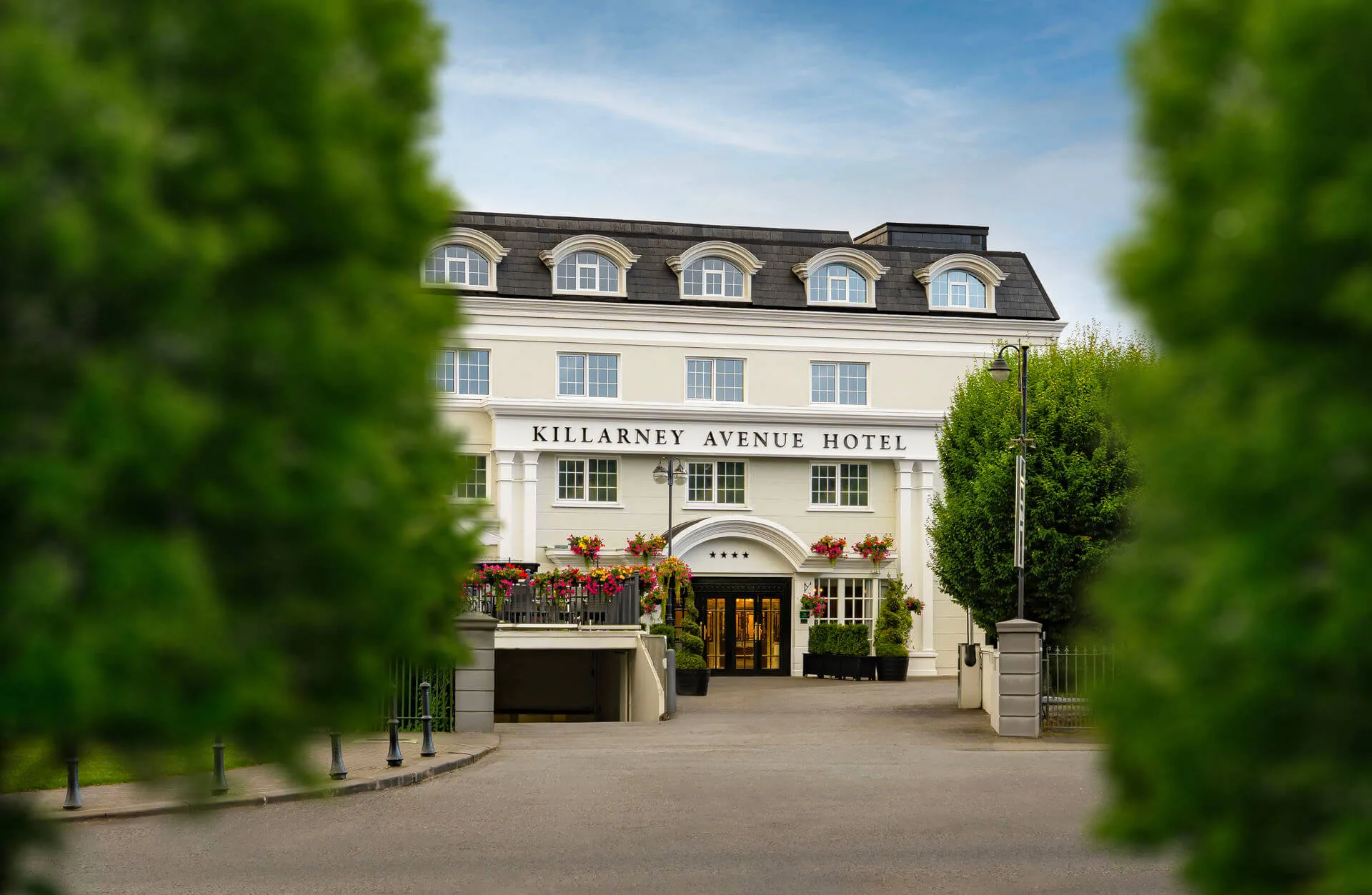 Elegant hotel entrance with guests arriving amidst lush greenery.