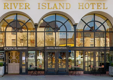 Entrance of River Island Hotel with inviting tables outside Cons Bar & Grill.