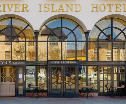 Entrance of River Island Hotel with inviting tables outside Cons Bar & Grill.