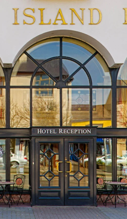 Entrance of River Island Hotel with inviting tables outside Cons Bar & Grill.