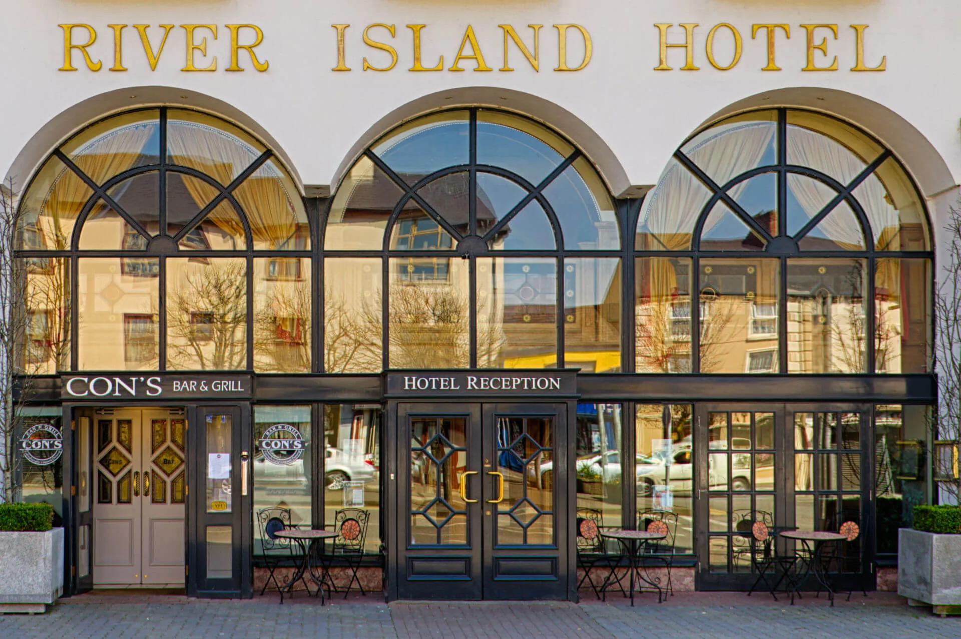 Entrance of River Island Hotel with inviting tables outside Cons Bar & Grill.