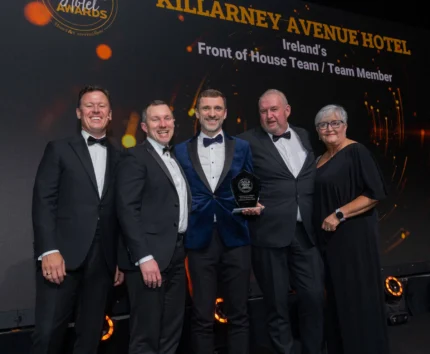 Group celebrating award on stage at Killarney Avenue Hotel event.