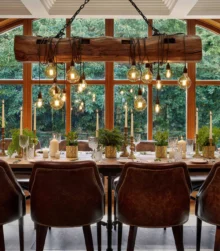 Cosy dining area set with elegant tableware, glowing lights, large window view of greenery.