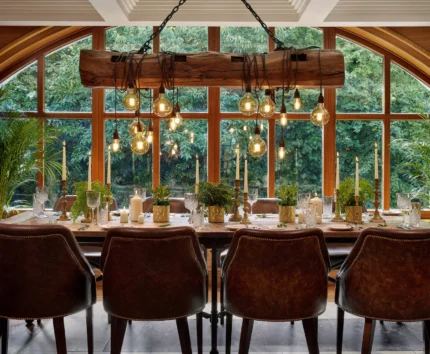 Cosy dining area set with elegant tableware, glowing lights, large window view of greenery.