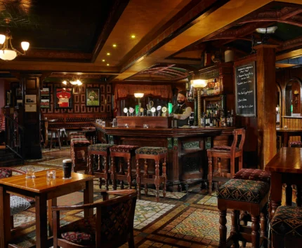Cosy pub interior with a welcoming bar, patrons enjoying drinks together.