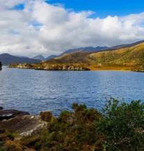 Scenic view of a tranquil lake surrounded by lush hills and a clear blue sky.