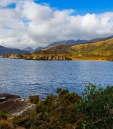 Scenic view of a tranquil lake surrounded by lush hills and a clear blue sky.
