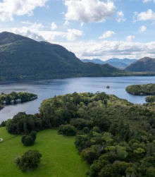 A scenic view of green hillsides and a tranquil lake under a partly cloudy sky.