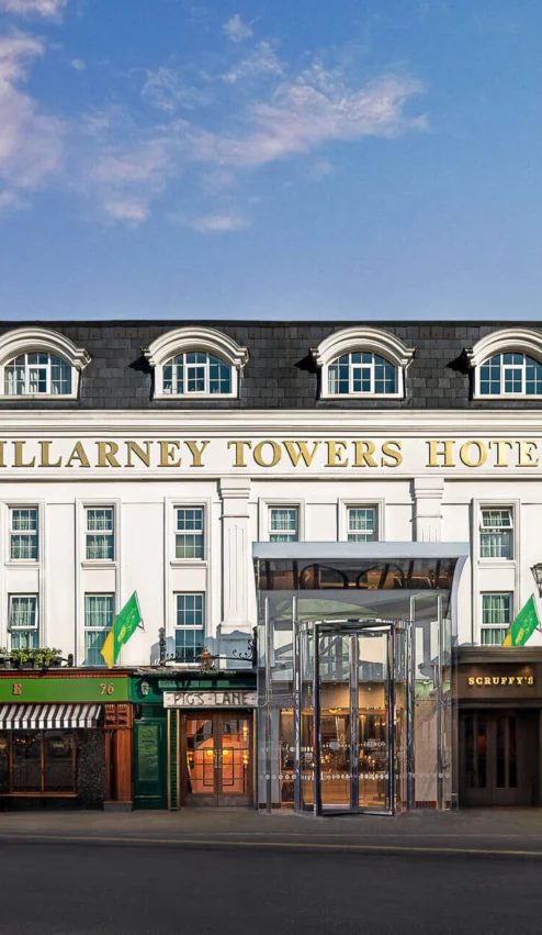 Elegant exterior of Killarney Towers Hotel under a blue sky.