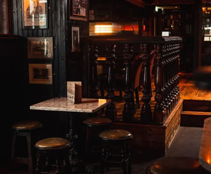 Cosy pub corner with rustic wooden stools and warm lighting.