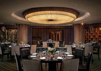 Elegant dining room set for a group, warm lighting, floral centrepieces.