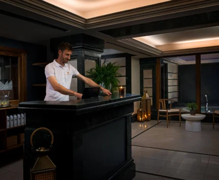 Friendly staff member at hotel reception counter, warmly welcoming guests.