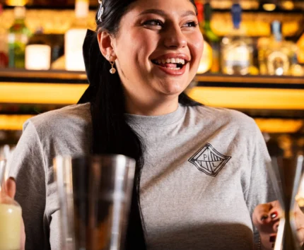 Smiling bartender in cosy pub setting with warm lighting.
