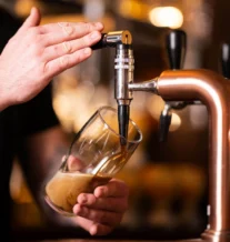 Bartender pouring a pint of beer in a cosy pub setting.