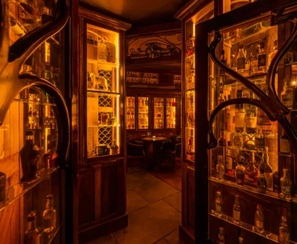 Cosy, warmly-lit hotel bar with elegant wooden shelves and intimate seating.
