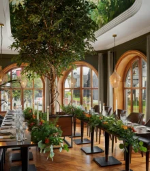 Elegant dining area with large windows and lush greenery, set for a group gathering.