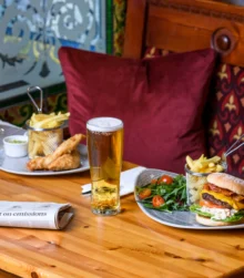 Cosy dining with burgers, drinks, and chips in a warm, inviting setting.