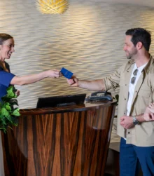 Friendly receptionist welcoming a couple at a stylish hotel check-in desk.
