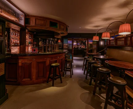 Cozy and inviting pub interior with warm lighting and wooden bar stools.