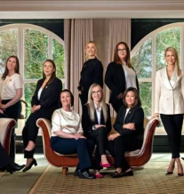 A warm and welcoming hotel team posing together in a spacious, elegantly furnished lounge.