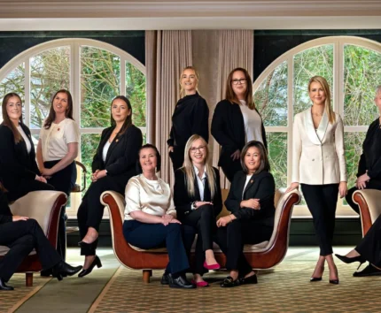 A warm and welcoming hotel team posing together in a spacious, elegantly furnished lounge.