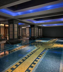 Luxurious indoor pool with mosaic tiles and ambient lighting at a hotel spa.