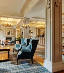 Elegant hotel lobby with cosy seating and chandeliers, welcoming guests at reception.