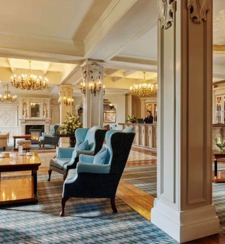 Elegant hotel lobby with cosy seating and chandeliers, welcoming guests at reception.