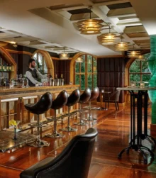 Luxurious hotel bar with wooden decor and bartender serving drinks.
