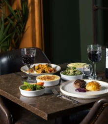 Elegant dining with diverse dishes and red wine in a cosy, inviting restaurant setting.