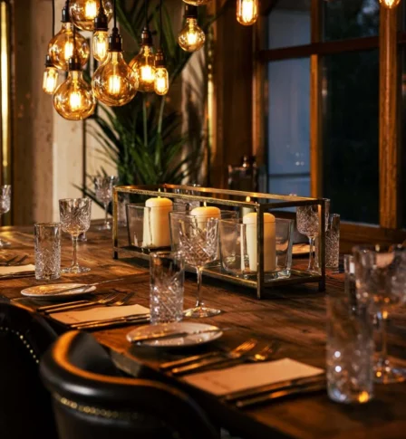 Elegant dining table set with candles and crystal glasses in a warm, inviting hotel setting.