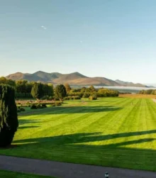 Family enjoying a stroll on lush hotel grounds with mountains in the distance.