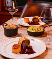 Elegant dinner setting with gourmet dishes and red wine in a cosy, inviting restaurant.