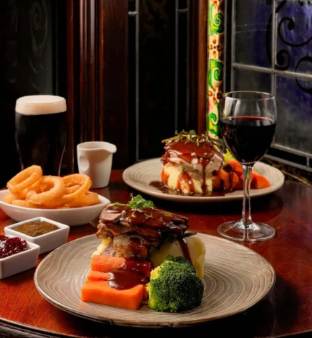 Cosy dining setting with plated roast dinners, wine, and pints, creating a warm, inviting atmosphere.
