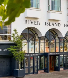 River Island Hotel entrance with welcoming glass doors and leafy surroundings.