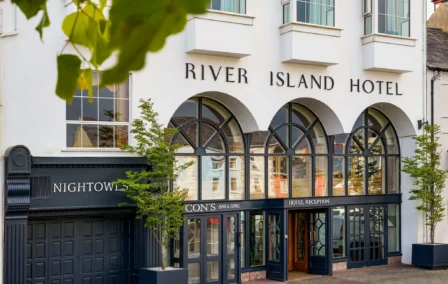 River Island Hotel entrance with welcoming glass doors and leafy surroundings.