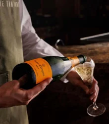 Bartender pouring champagne into a glass at a cosy hotel bar.